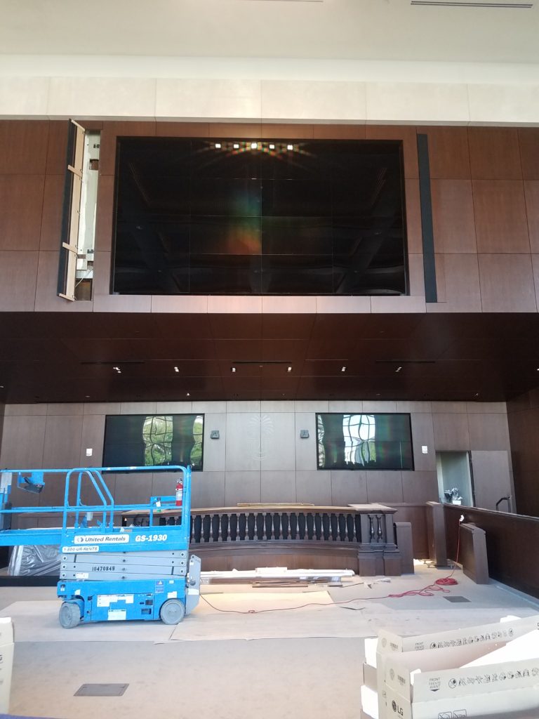 wall of wood paneling with three monitor screens and a judge's bench