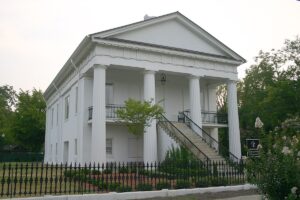 modern photo of classic white two-story building; historic marker in front